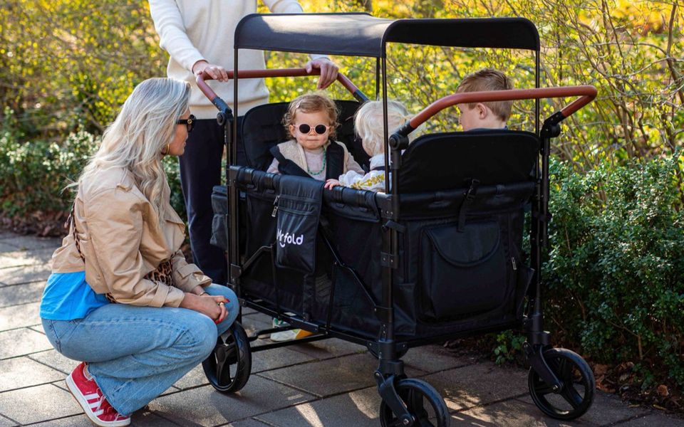 Parents looking at a Mr Fold stroller wagon with children inside